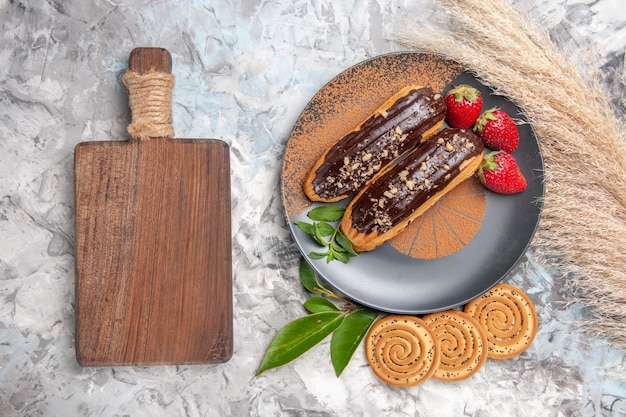 Bovenaanzicht heerlijke choco-eclairs met koekjes op een lichtwit tafelcake-koekjesdessert