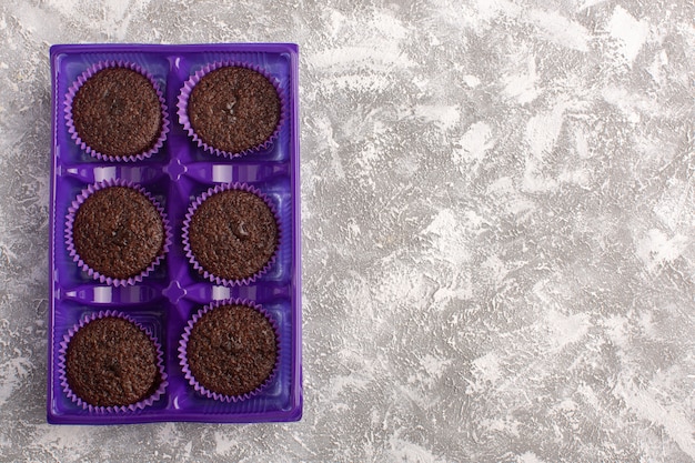 Bovenaanzicht heerlijke chocolade brownies in paars pakket op het licht bureau cake chocolade thee bak deeg