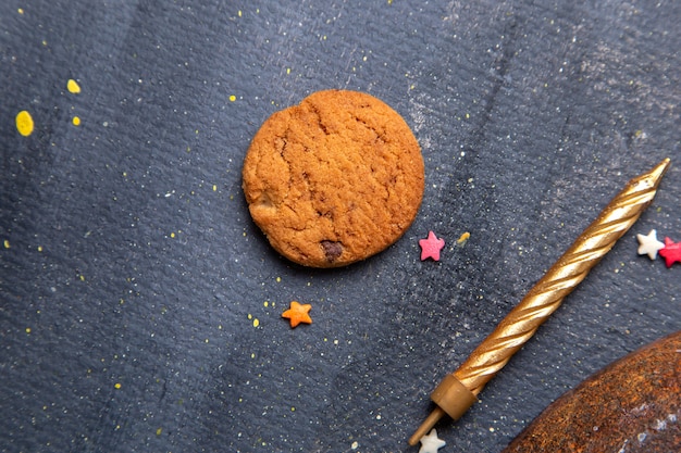 Bovenaanzicht heerlijke chocoladekoekje met gouden kaars op de donkere achtergrond cookie biscuit suiker thee zoet