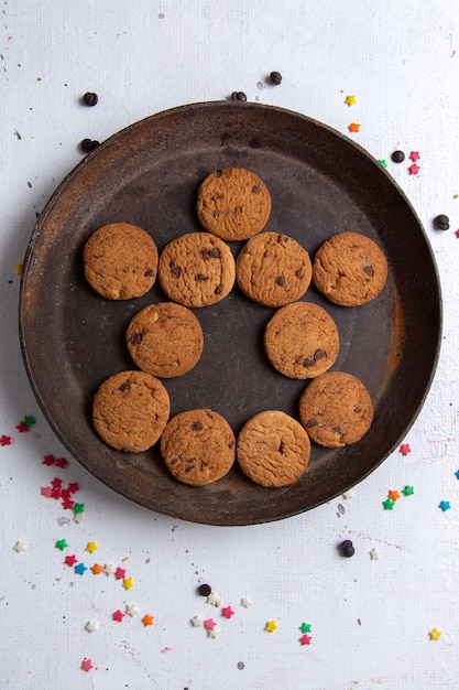 Bovenaanzicht heerlijke chocoladekoekjes in donkere ronde plaat op de witte achtergrond cookie koekje suiker zoete thee