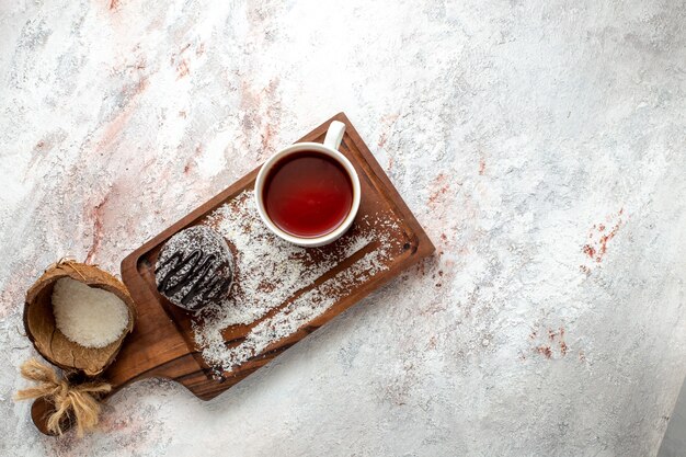 Bovenaanzicht heerlijke chocoladetaart met kopje thee op witte achtergrond chocoladetaart koekje suiker zoete koekjesthee