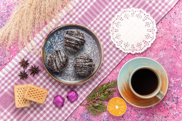 Bovenaanzicht heerlijke chocoladetaarten met kopje thee en wafels op roze