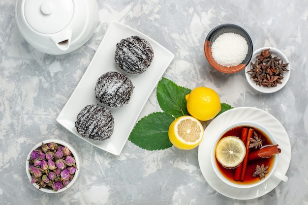 Bovenaanzicht heerlijke chocoladetaartjes kleine ronde gevormd met citroen en kopje thee op witte ondergrond fruitcake koekje zoete suiker bak cookie