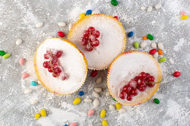 Bovenaanzicht heerlijke cranberry-taarten met rode veenbessen bovenop suikerstukjes en suikerpoeder met snoepjes licht bureau cake koekje zoet bakken