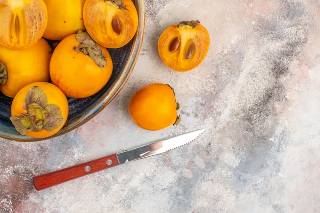 Bovenaanzicht heerlijke dadelpruimen in een kom persimmon en mes op naakte achtergrond