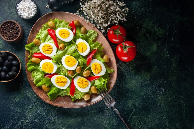 Bovenaanzicht heerlijke eiersalade bestaat uit olijven en groene salade op donkere achtergrond