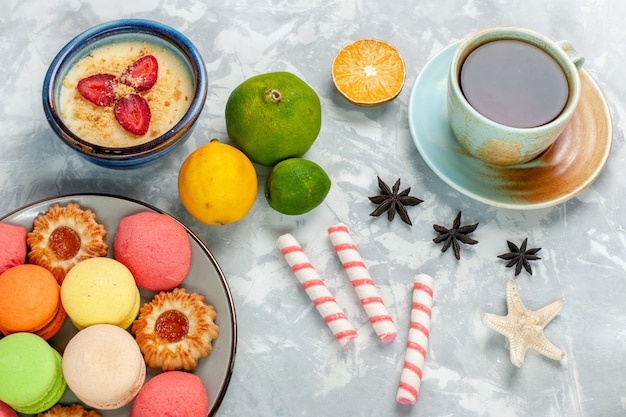 Bovenaanzicht heerlijke franse macarons met koekjes dessert en thee op licht wit bureau bakken cake koekjes suiker zoete foto