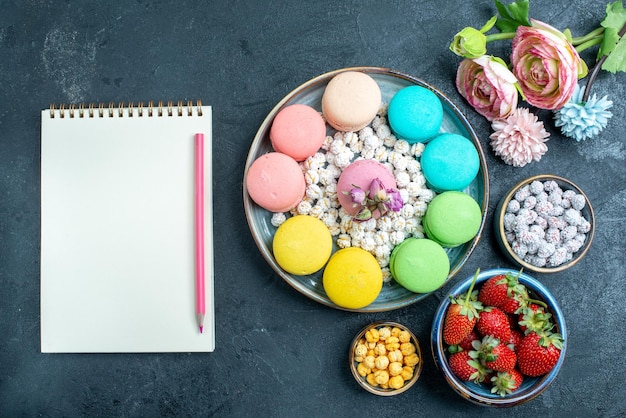 Bovenaanzicht heerlijke Franse macarons met snoepjes in lade op de donkere ruimte