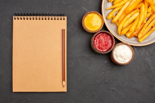 Bovenaanzicht heerlijke frietjes met kruiden op donkere achtergrond schotel aardappel fastfood hamburger maaltijd burger