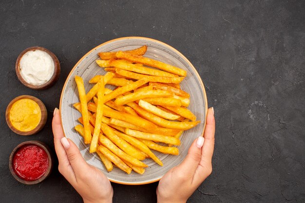 Bovenaanzicht heerlijke frietjes met kruiden op een donkere achtergrond aardappelmaaltijd fastfood schotel burger