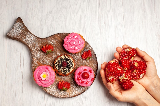 Bovenaanzicht heerlijke fruitcakes romige desserts met granaatappels op witte achtergrond cream tea zoet dessert cake cookie