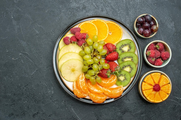 Bovenaanzicht heerlijke fruitsamenstelling vers en gesneden fruit op de donkere achtergrond rijp vers gezondheidsdieet fruit zacht