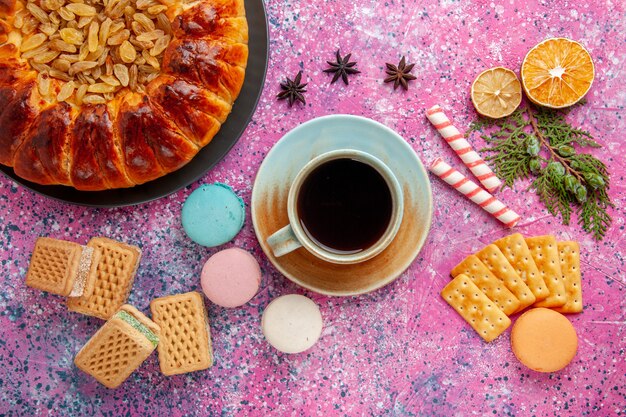 Bovenaanzicht heerlijke gebakjecake met rozijnen, theewafels en crackers op roze bureau