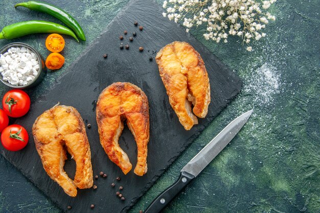 Bovenaanzicht heerlijke gebakken vis op een donkere ondergrond schotel salade bak vlees zee peper eten koken maaltijd zeevruchten