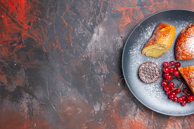 Bovenaanzicht heerlijke gesneden taart met rode bessen op de donkere tafel taart zoete cake