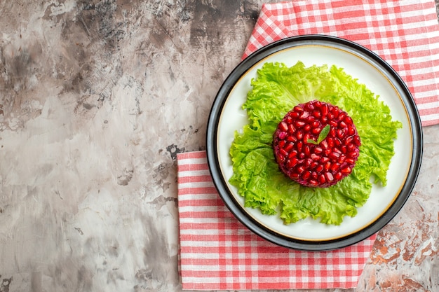 Bovenaanzicht heerlijke granaatappelsalade rond gevormd op groene salade op lichte achtergrond
