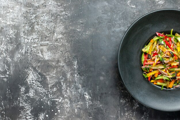 Bovenaanzicht heerlijke groentesalade binnen plaat op de grijze achtergrond