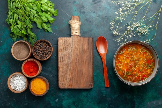 Bovenaanzicht heerlijke groentesoep met verschillende smaakmakers op het donkergroene oppervlak van het product van het ingrediënt van de groentesoep van de voedselmaaltijd