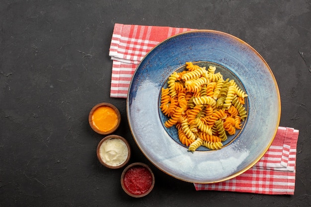 Bovenaanzicht heerlijke italiaanse pasta ongebruikelijke gekookte spiraal pasta op de donkere achtergrond pasta gerecht maaltijd koken diner