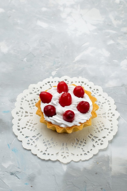 Bovenaanzicht heerlijke kleine cake met room en rood fruit op het grijze oppervlak zoet fruit