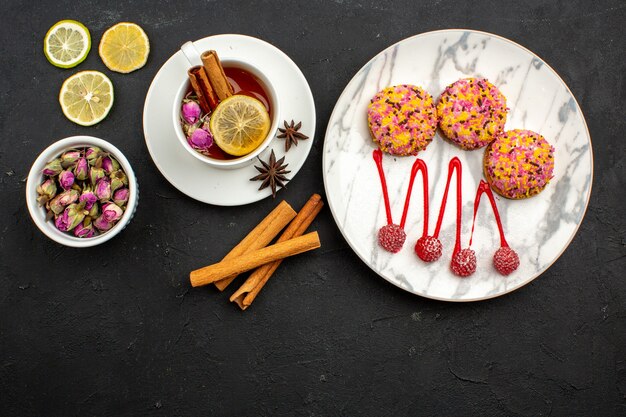 Bovenaanzicht heerlijke kleine koekjes met thee en kaneel op grijze ruimte