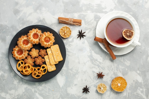 Bovenaanzicht heerlijke koekjes met crackers en chips in plaat met kopje thee op wit bureau koekje koekje suiker zoete thee knapperig