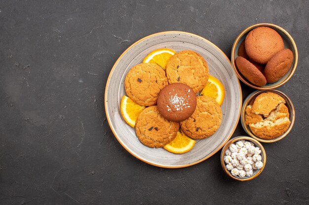 Bovenaanzicht heerlijke koekjes met vers gesneden sinaasappels op donkere achtergrond koekjeskoekje fruit zoete citruscake