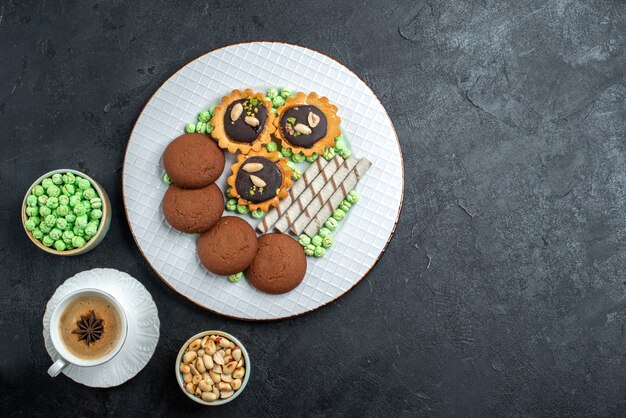 Bovenaanzicht heerlijke koekjes met verschillende snoepjes op donkergrijze achtergrond suikerkoekje zoete cake taartkoekje