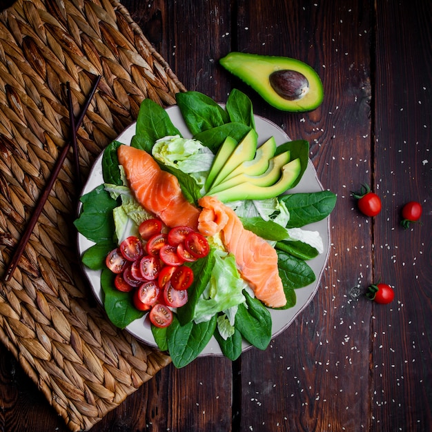 Bovenaanzicht heerlijke maaltijd in plaat met stokjes en avocado op houten achtergrond.