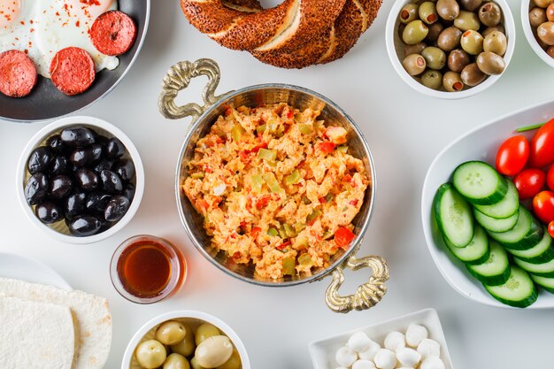 Bovenaanzicht heerlijke maaltijden in pan met salade, augurken, Turkse bagel op wit oppervlak