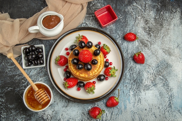 Bovenaanzicht heerlijke pannenkoeken met fruit en honing op de lichte ondergrond zoete fruitcake