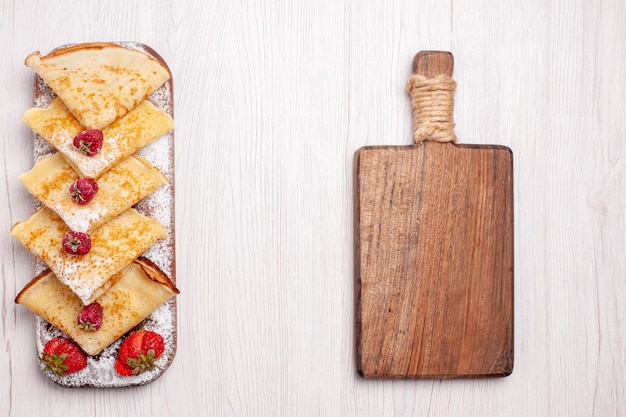 Gratis foto bovenaanzicht heerlijke pannenkoeken met fruit op wit bureau zoet dessert fruit pannenkoek suiker