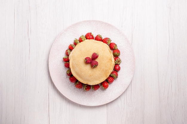 Bovenaanzicht heerlijke pannenkoeken met verse rode aardbeien op een witte achtergrond fruitcake, bessentaart, zoete koekjessuiker