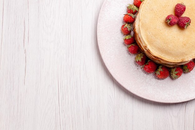 Bovenaanzicht heerlijke pannenkoeken met verse rode aardbeien op witte achtergrond fruittaart cake berry biscuit suiker zoet