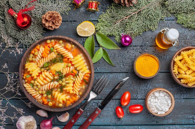 Bovenaanzicht heerlijke pastasoep van spiraalvormige Italiaanse pasta op donkerblauwe rustieke bureaukeuken soep pasta kleurschotel