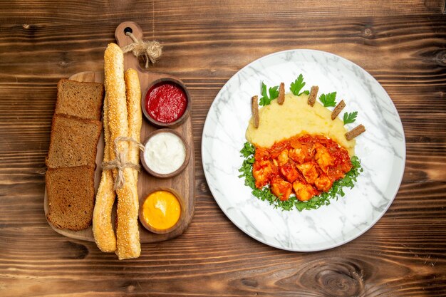 Bovenaanzicht heerlijke plakjes kip met aardappelpuree brood en kruiden op houten bureau aardappelmaaltijd eten pittige peper