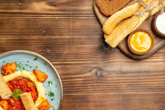 Bovenaanzicht heerlijke plakjes kip met aardappelpuree en brood op een houten bureau aardappelmaaltijd eten pittige peper