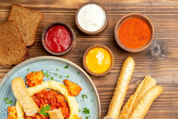 Gratis foto bovenaanzicht heerlijke plakjes kip met aardappelpuree en smaakmakers op houten bureau aardappelmaaltijd eten pittige peper