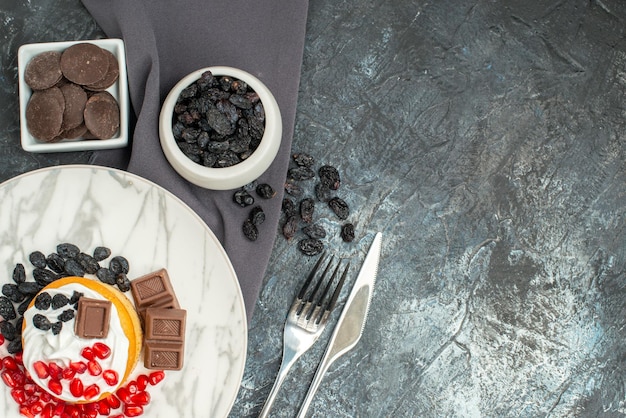 Bovenaanzicht heerlijke romige cake met chocolade en rozijnen op licht-donkere achtergrond