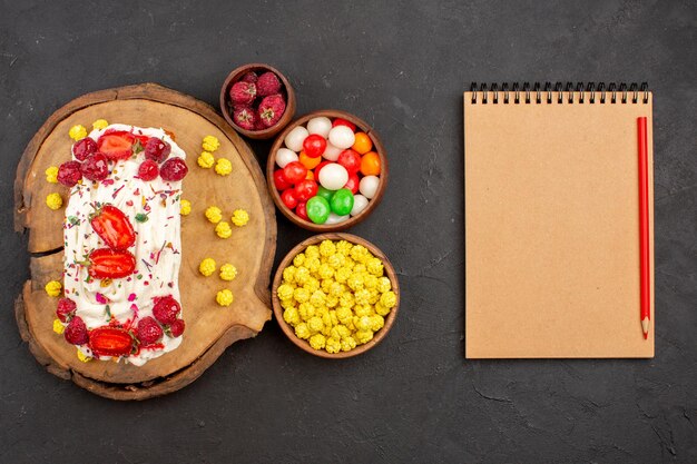 Bovenaanzicht heerlijke romige cake met fruit en snoep op donkere vloer biscuit thee koekjes cake zoete room