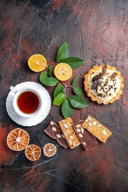 Bovenaanzicht heerlijke romige cake met kopje thee op de donkere tafel zoete cake dessert