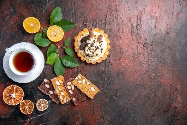 Bovenaanzicht heerlijke romige cake met kopje thee op de donkere tafel zoete cake dessert