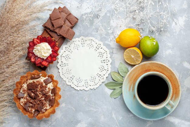 Bovenaanzicht heerlijke romige taarten met chocoladerepen citroenen op het witte bureau cake koekje zoete suiker bakken