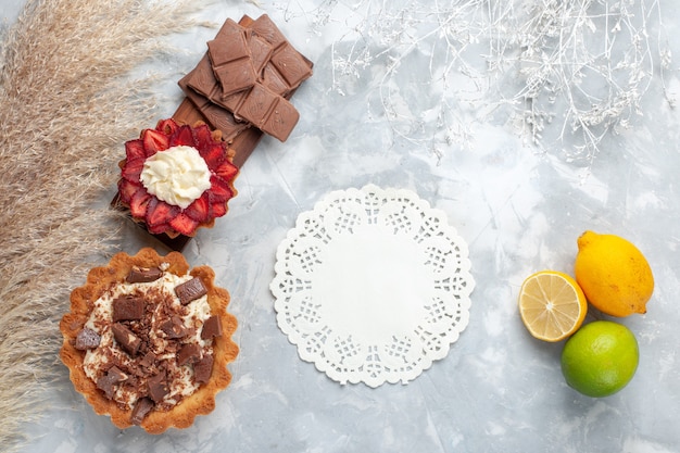 Bovenaanzicht heerlijke romige taarten met citroen en chocoladerepen op het witte bureau cake koekje zoete suiker bakken