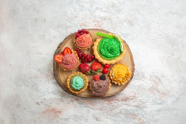 Bovenaanzicht heerlijke romige taarten met fruit op een witte tafel taart dessert zoet