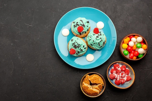 Bovenaanzicht heerlijke romige taarten met snoepjes op de donkere achtergrond cake dessert biscuit snoep koekjes kleur