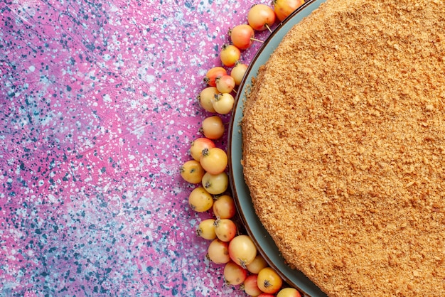 Bovenaanzicht heerlijke ronde cake binnen plaat met beklede zoete kersen op felroze bureau cake pie biscuit zoet bakken