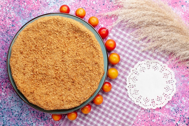 Bovenaanzicht heerlijke ronde cake binnen plaat met omzoomde kersenpruimen op het felroze bureau taart taart biscuit zoet bak fruit