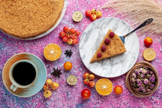 Bovenaanzicht heerlijke ronde cakeplak ervan in plaat met kopje thee op het felroze bureau cake fruittaart koekje zoet bakken