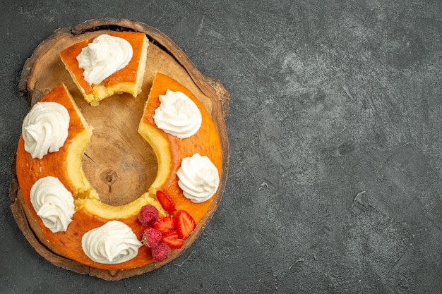 Gratis foto bovenaanzicht heerlijke ronde taart gesneden met witte room op grijze achtergrond koekjes biscuit taart taart zoete thee